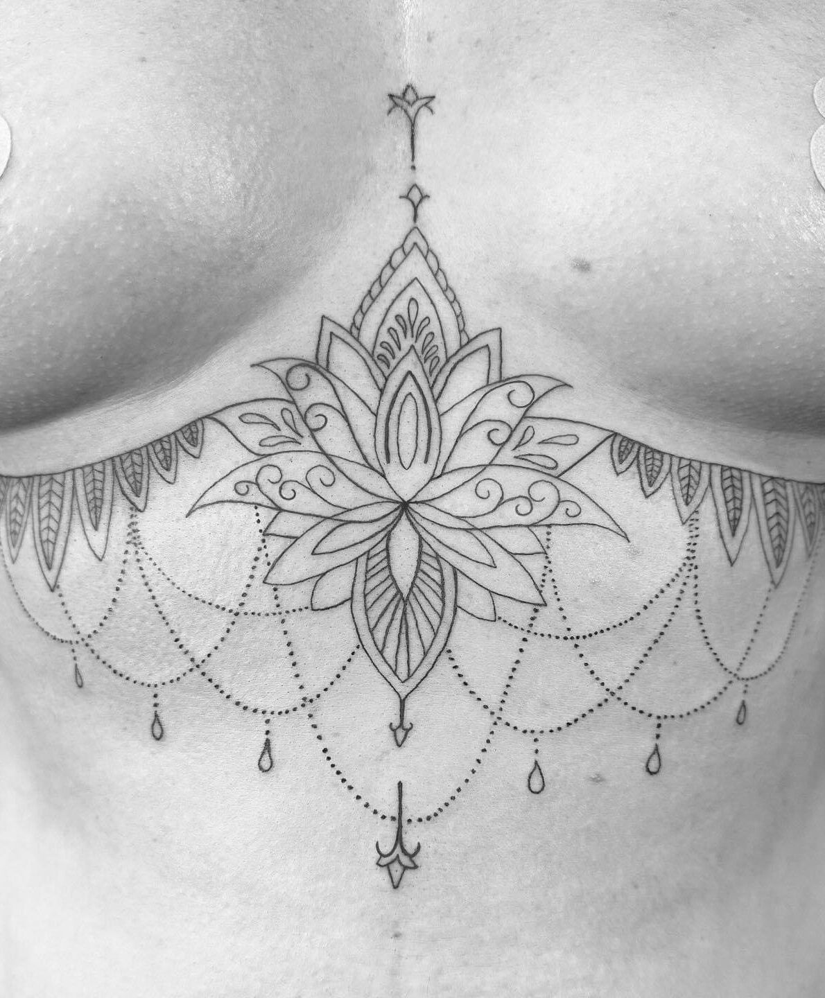 Lotus flower mandala tattoo on a women's sternum / chest by tattoo artist Marcus Kingsland at Markings Tattoos in Beverley, East Riding of Yorkshire.