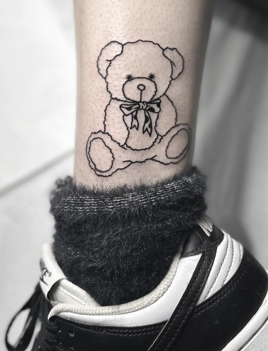 Fine line teddy bear tattoo by tattoo artist Marcus Kingsland at Markings Tattoos in Beverley, East Riding of Yorkshire.